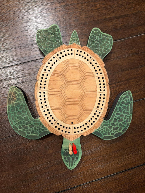 Turtle-shaped wooden cribbage board on a wooden surface