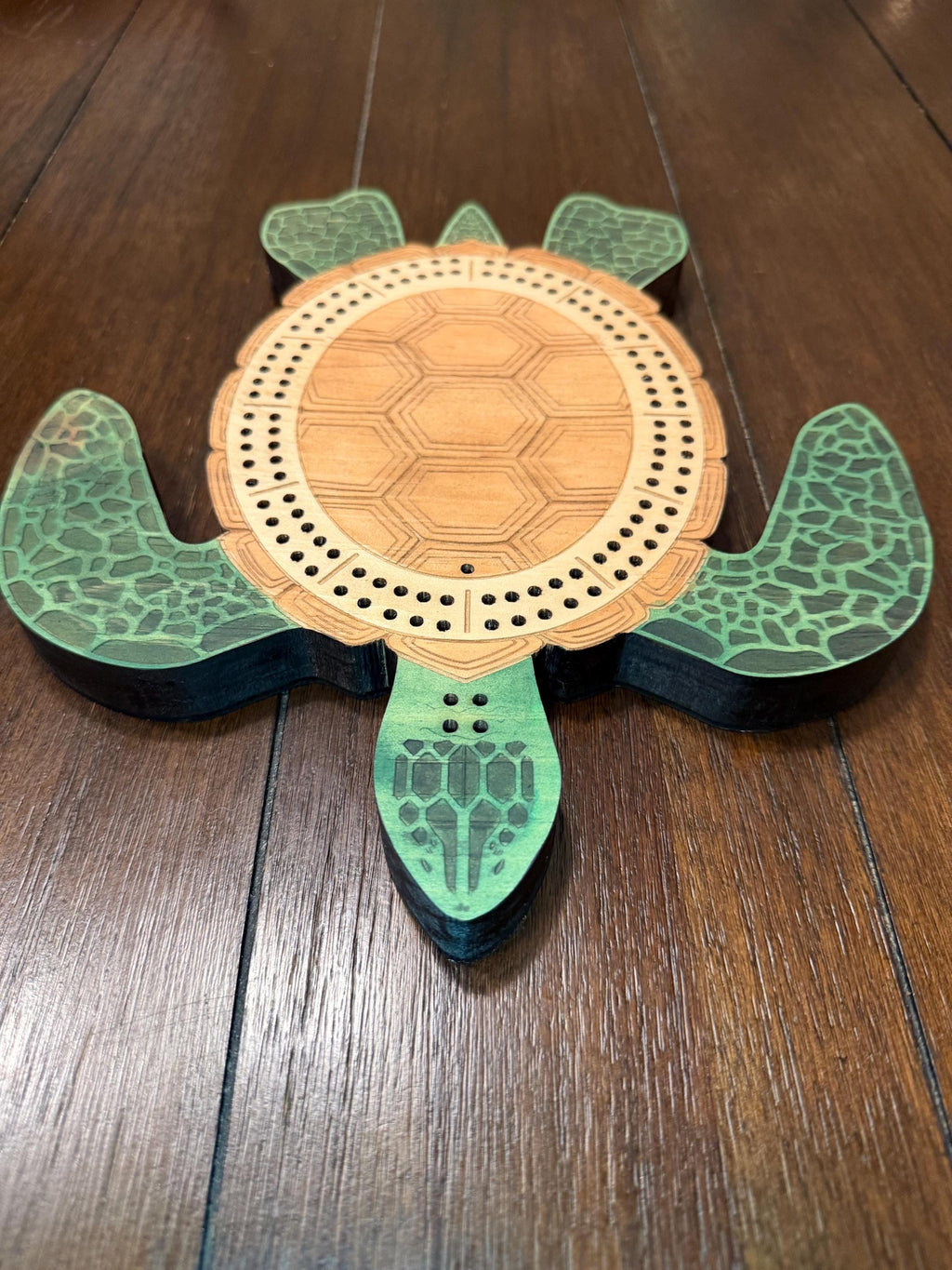 Angled overhead view of a handcrafted turtle cribbage board emphasizing the engraved shell design, layered construction, and decorative flippers.