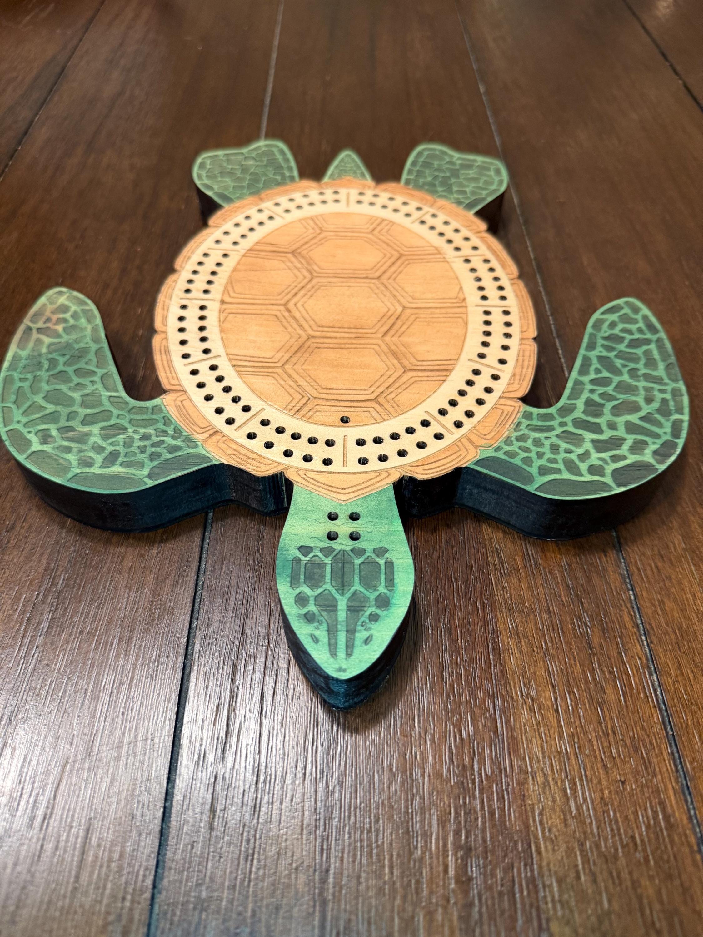 Angled overhead view of a handcrafted turtle cribbage board emphasizing the engraved shell design, layered construction, and decorative flippers.