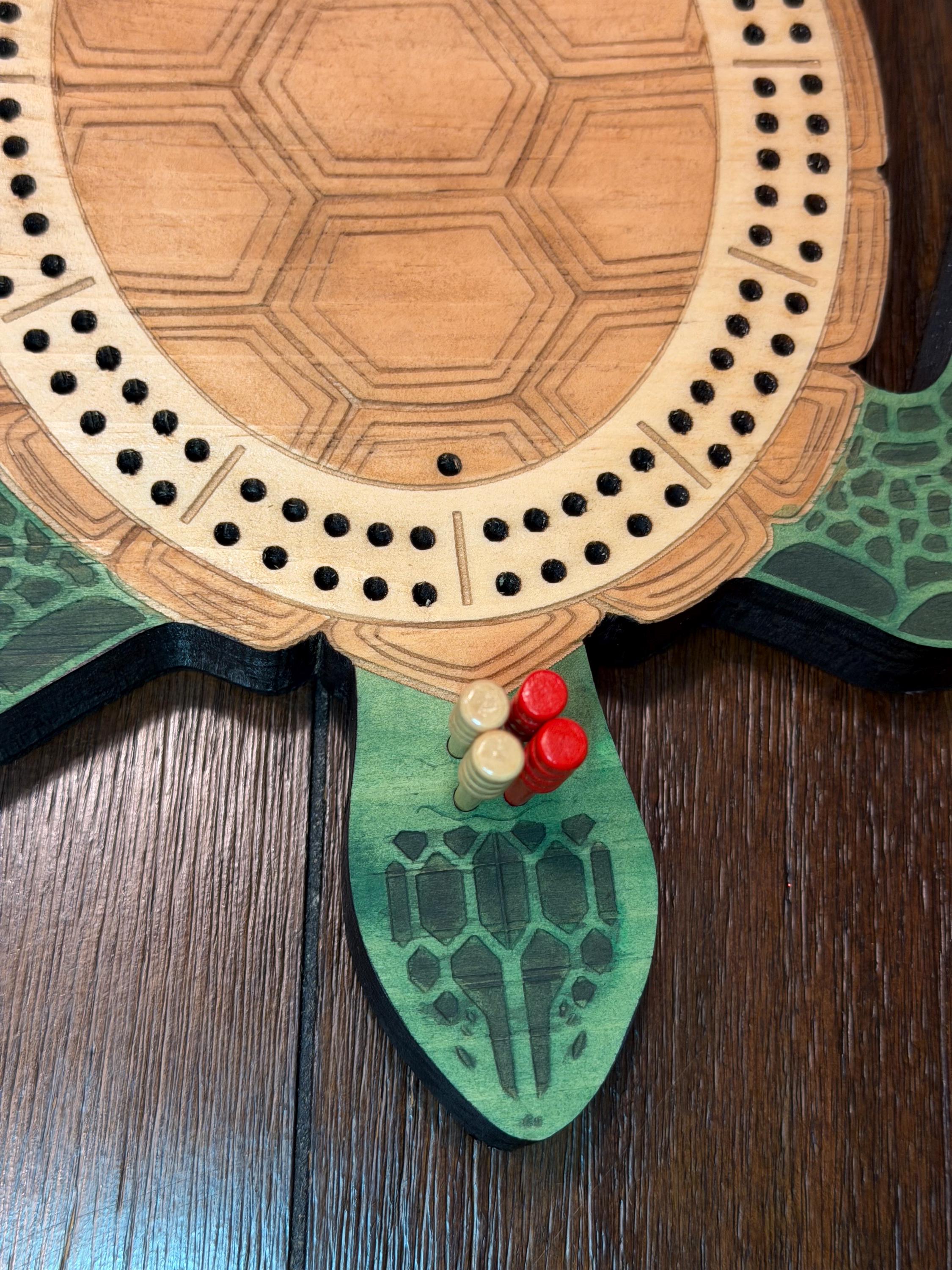 Close up of a wooden turtle-shaped cribbage board with pegs on a wooden surface