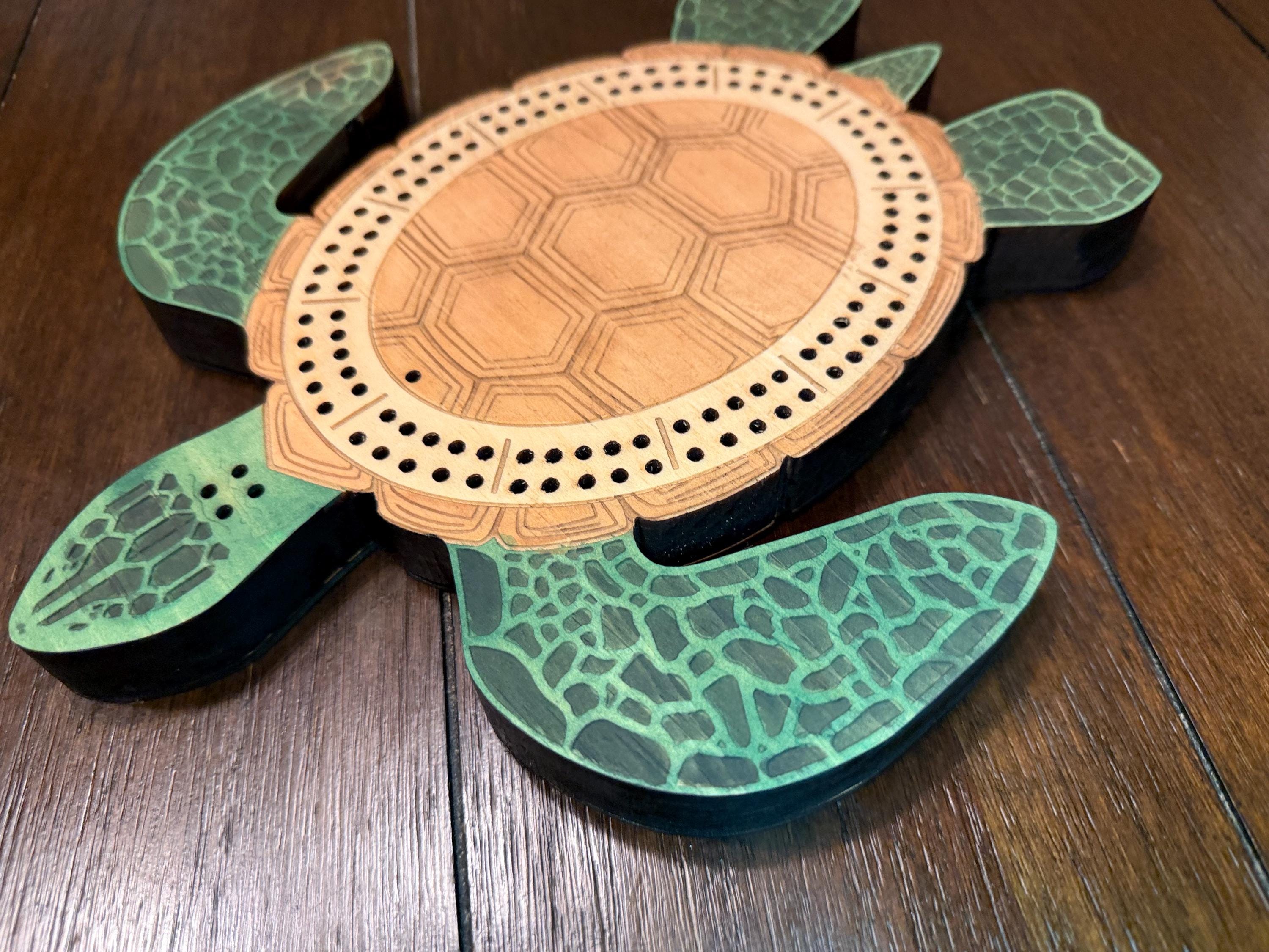 Side perspective of a turtle-shaped cribbage board highlighting the sculpted flippers, engraved shell pattern, and raised wood layers.