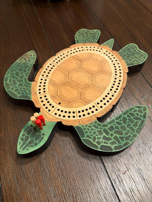 Wooden turtle-shaped cribbage board on a wooden surface